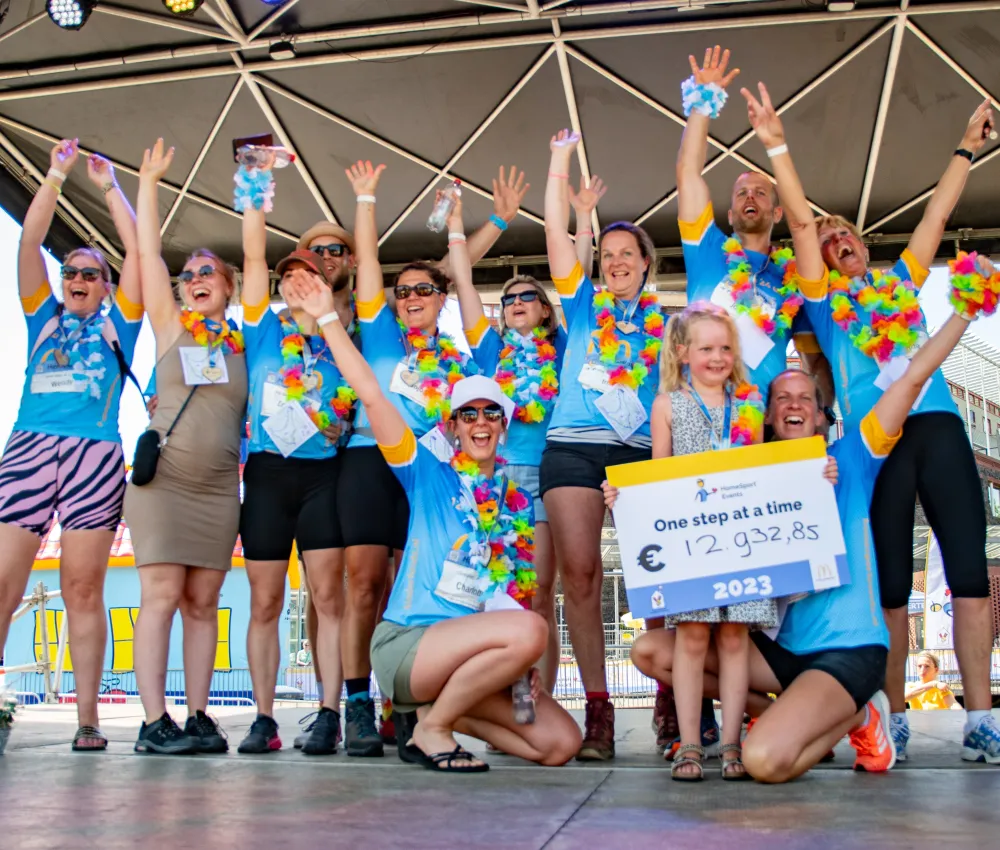 HomeSport Events team bij de finish met cheque op het podium