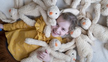 Meisje omringd door Kinderfondsknuffels